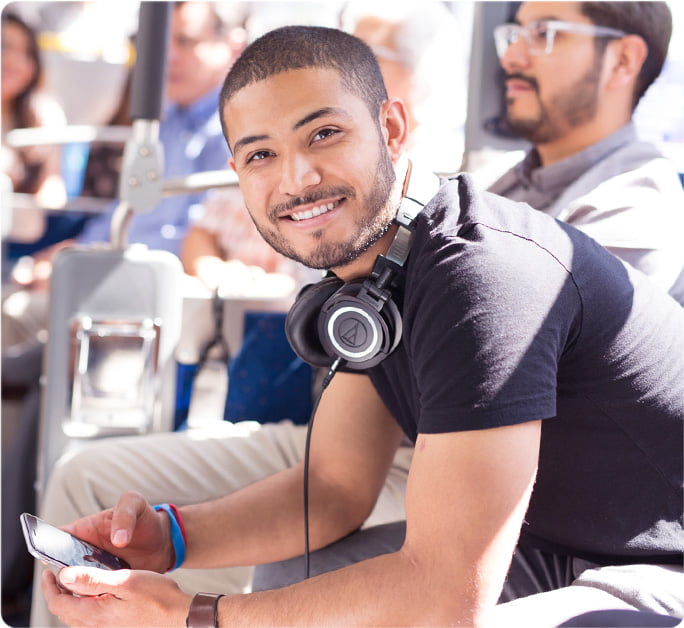 Smiling young man sits on the OC bus with headphones