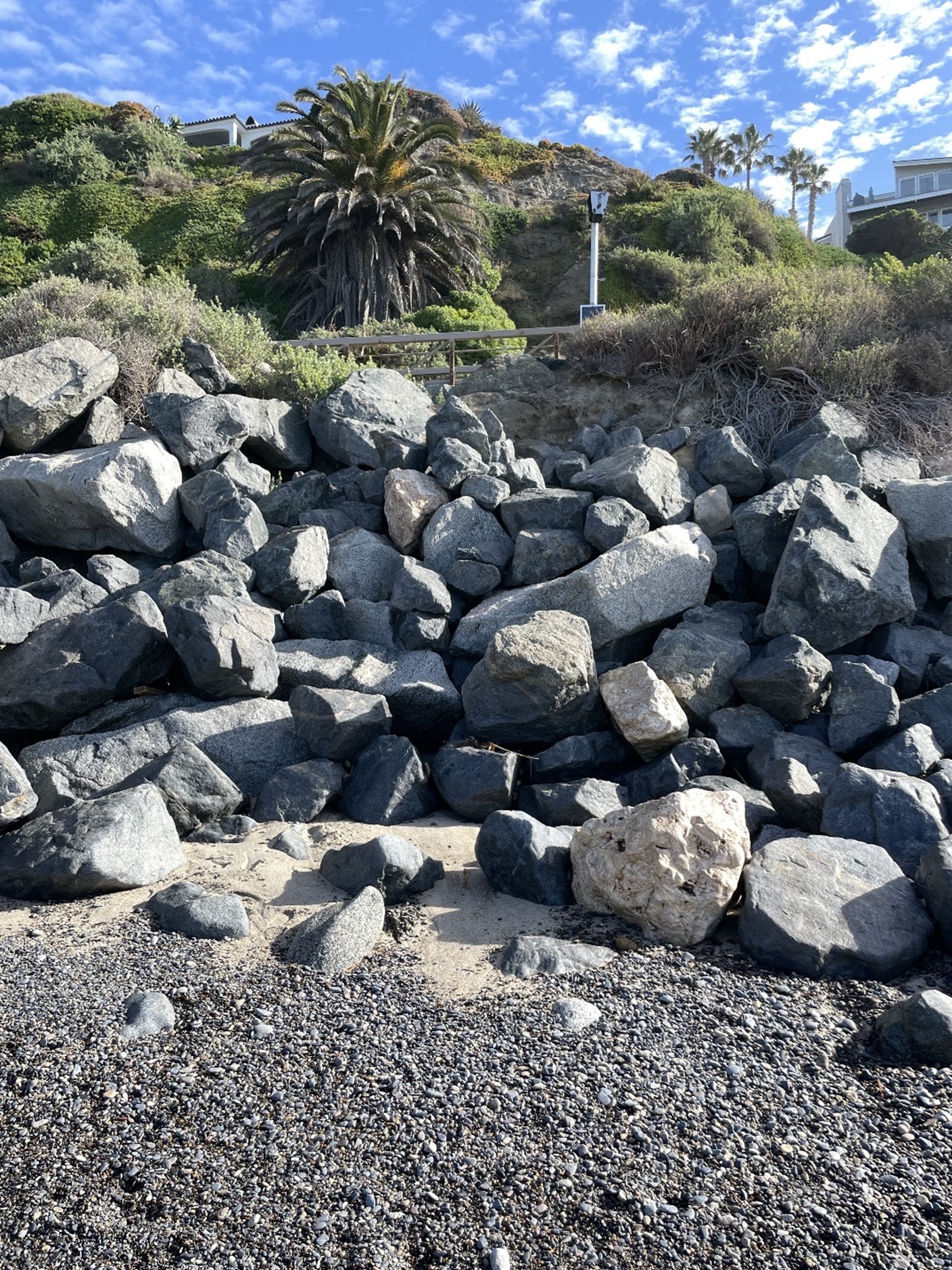 Undersized and displaced stones and exposed natural embankment at south end of repair area