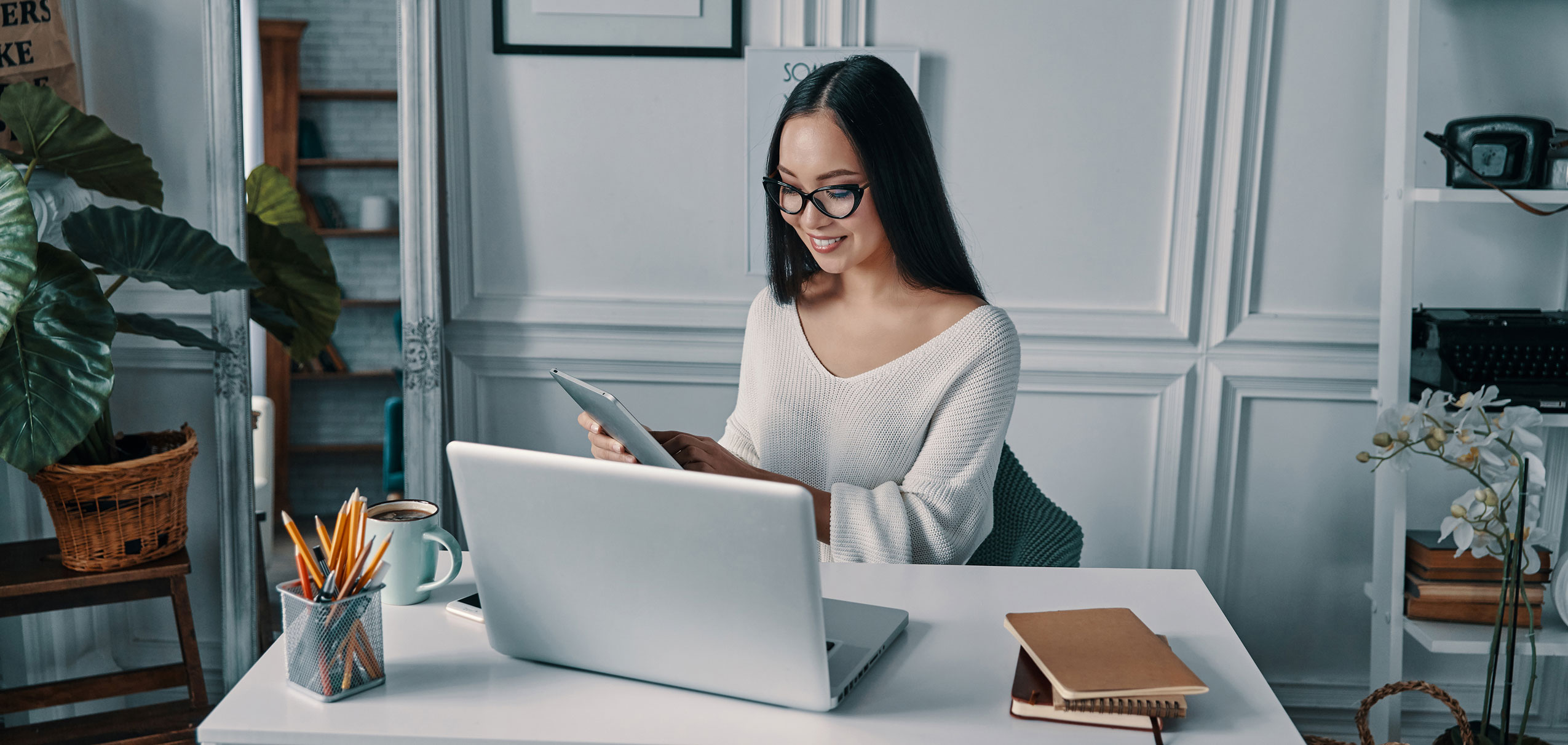 A young woman smiles at her phone while working from home